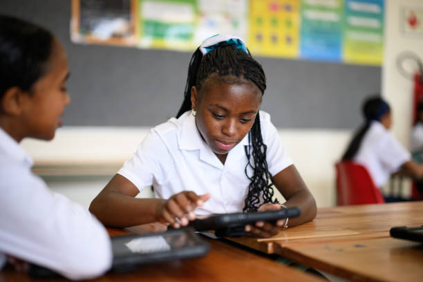 Schoolgirl sitting at group desk working on digital tablet Schoolgirl sitting at group desk working on digital tablet